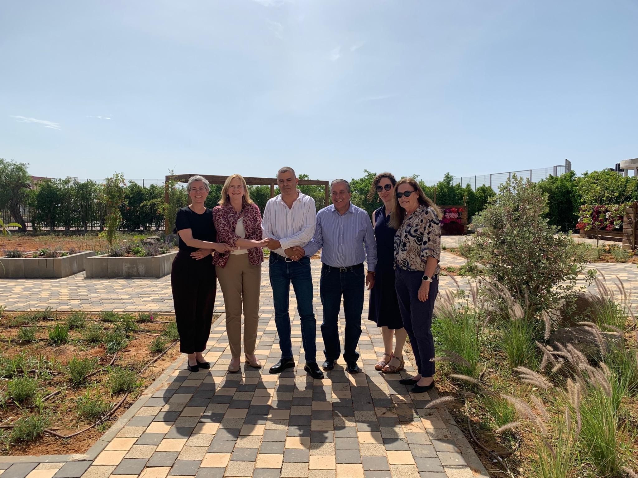 Six colleagues standing together outdoors on a paved walkway